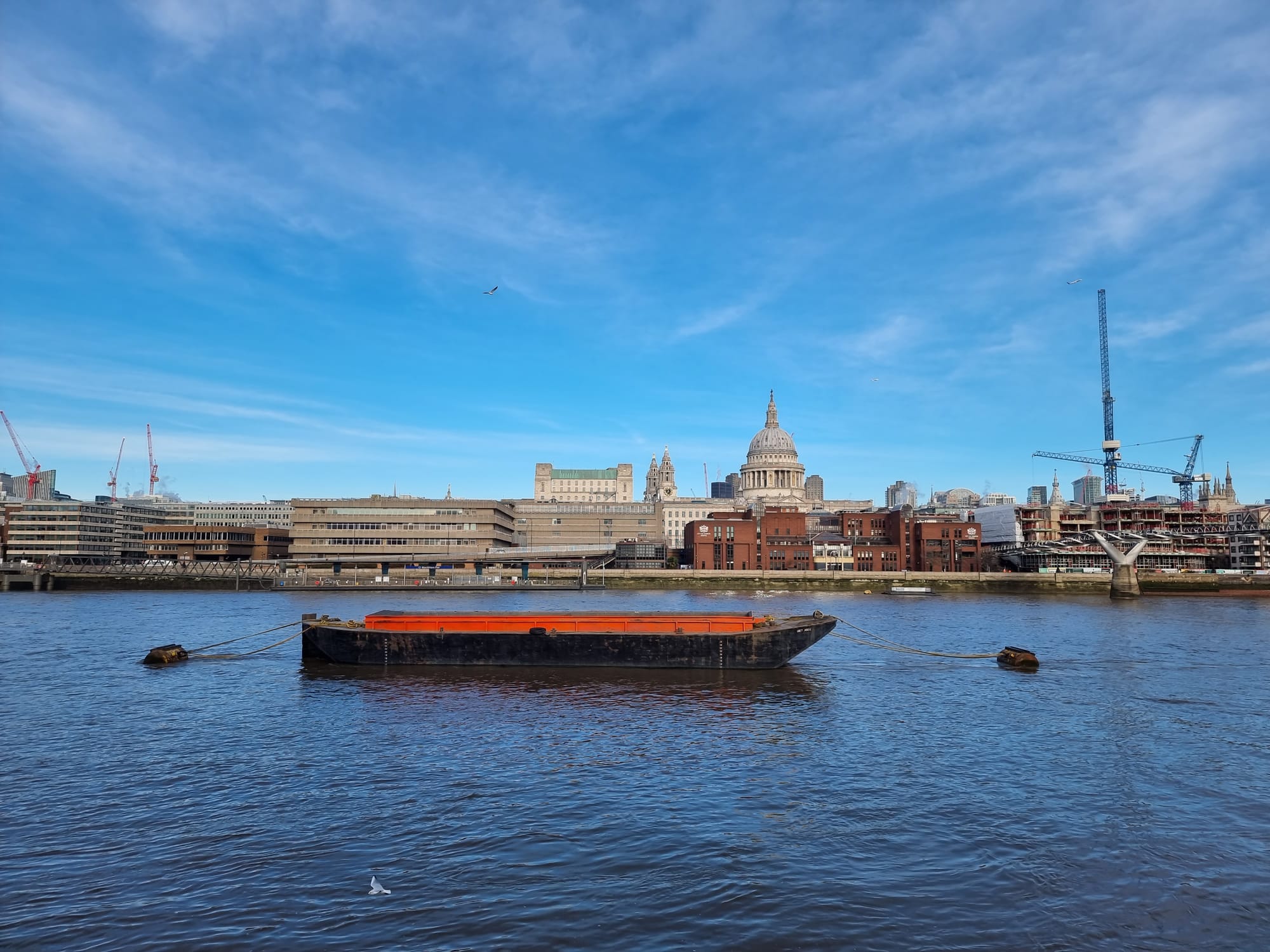 View across the Thames towards St. Paul's Cathedral, with a boat in the centre.