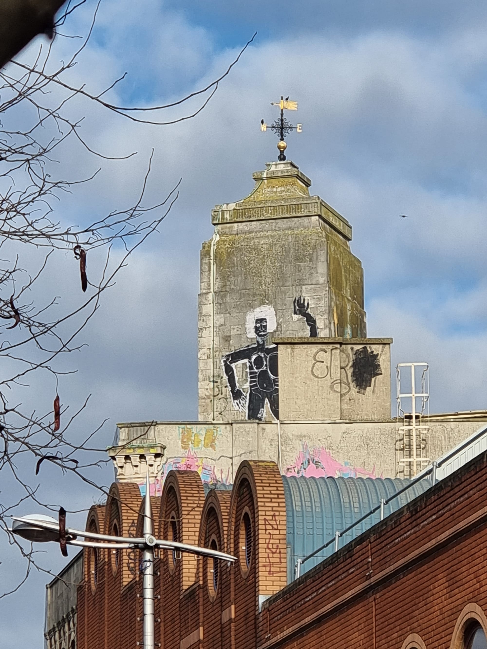 A painted figure, black body, white hair, on a tower high up above Peckham high street.