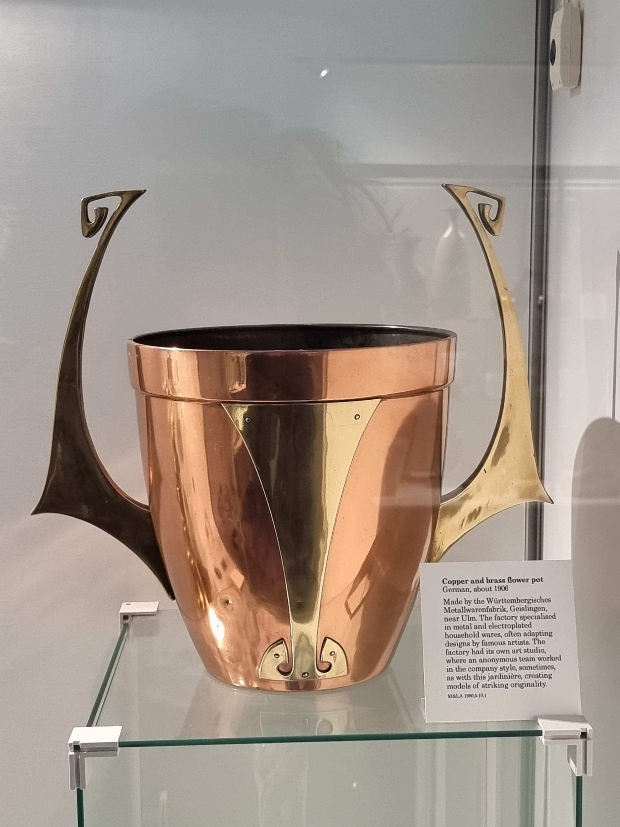 A copper and brass flower pot from the early 20th century, which is reminiscent of an upturned Mandalorian helmet