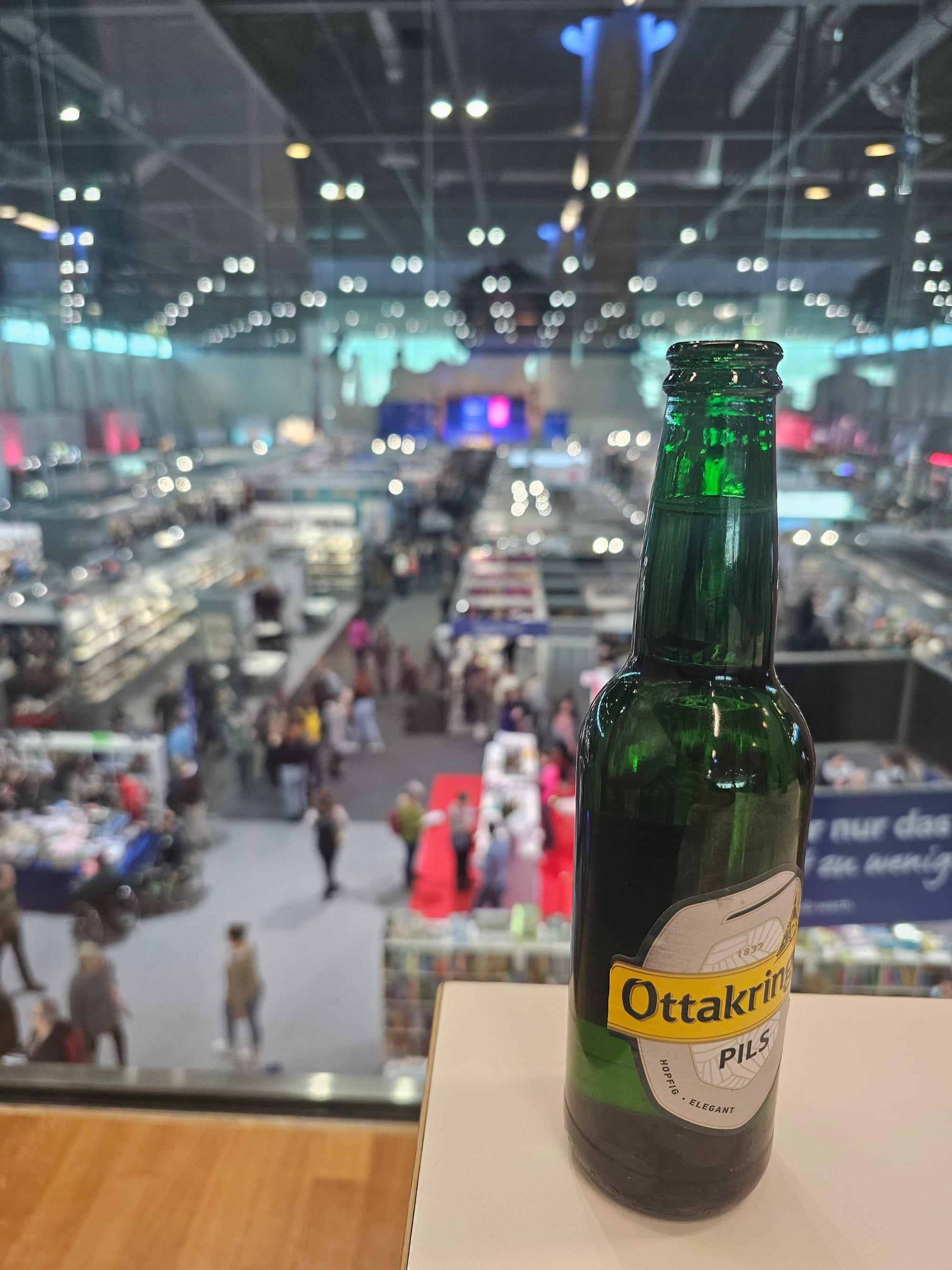 View from the gallery onto Buch Wien exhibition. In the foreground a bottle of beer 