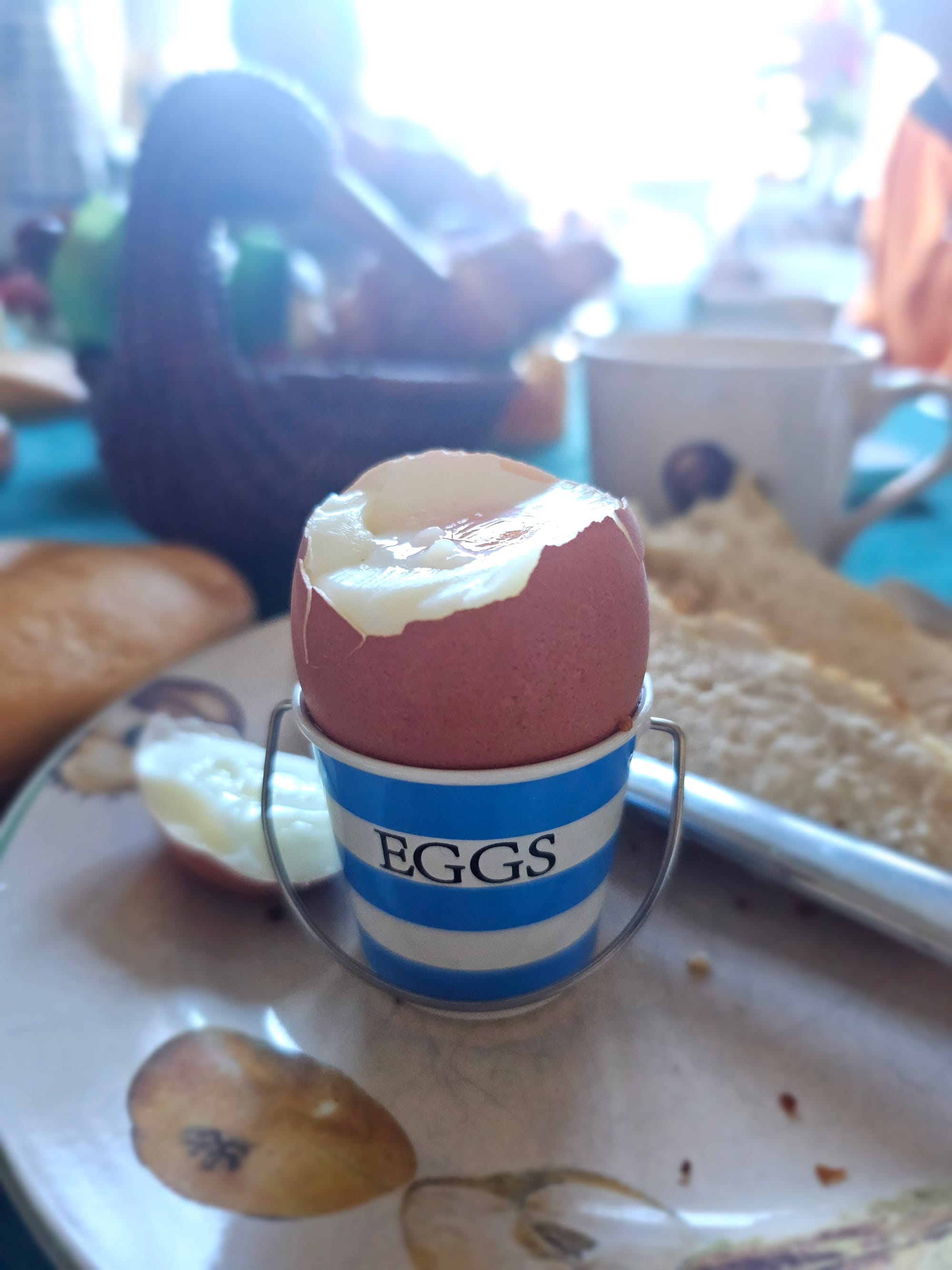 A decapitated egg in a lil bucket that says EGGS 