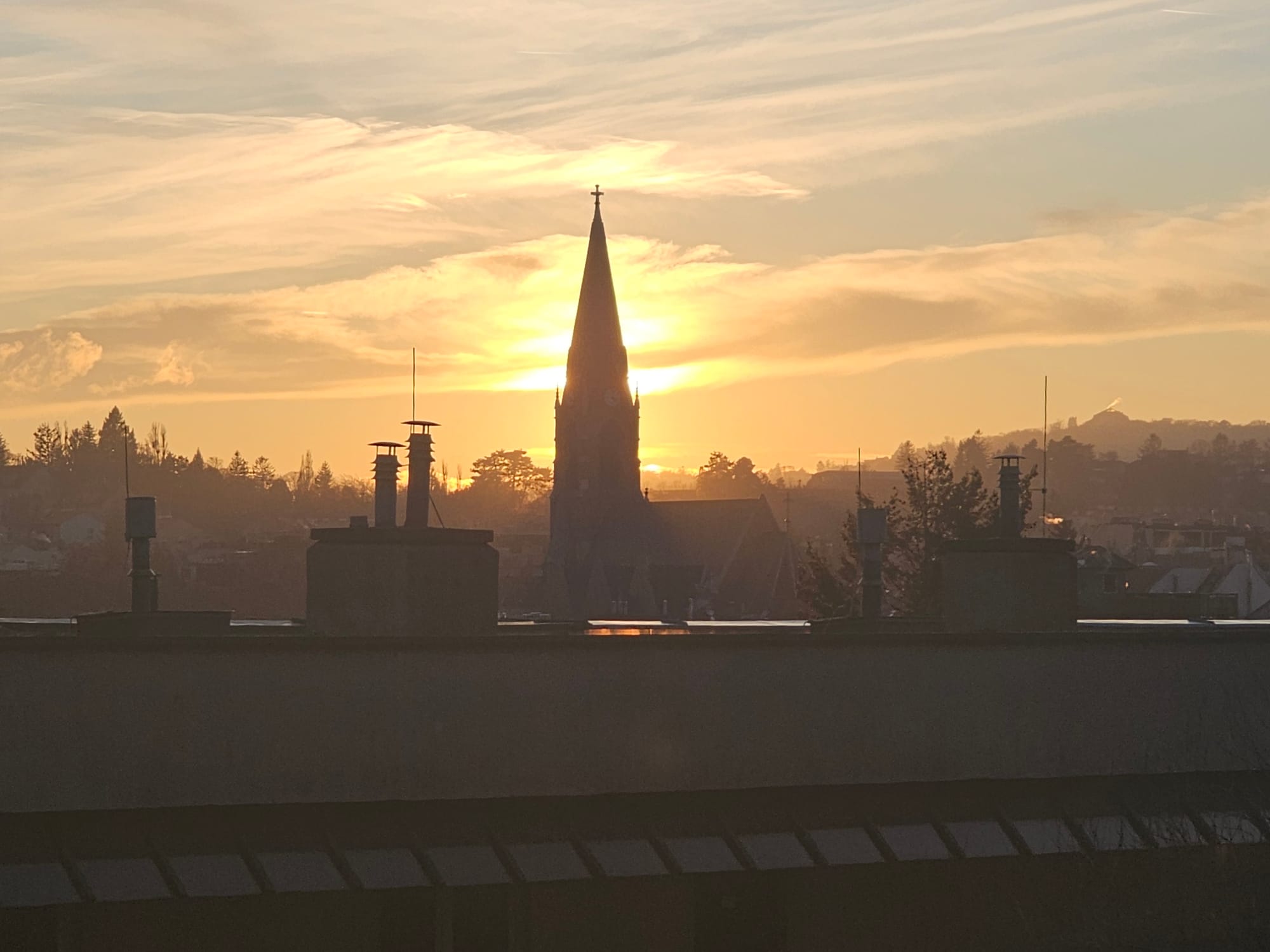 A church tower before the background of a golden afternoon sun 