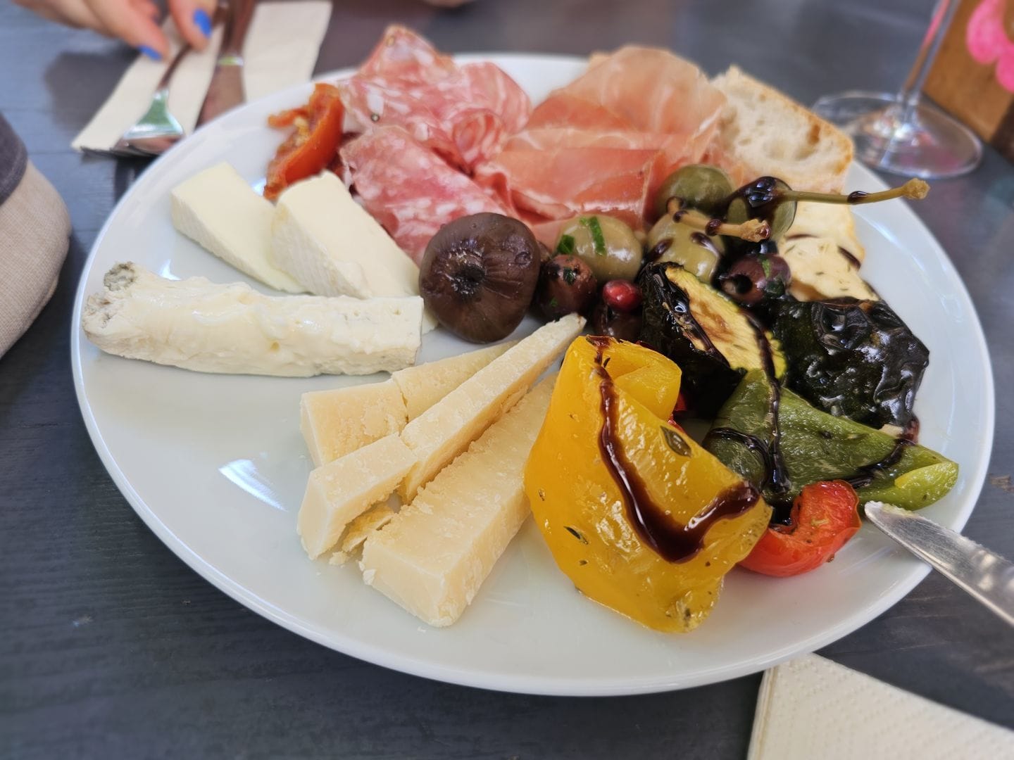 A plate of antipasti, with plenty of cheese, prosciutto and salami, also various vegetables
