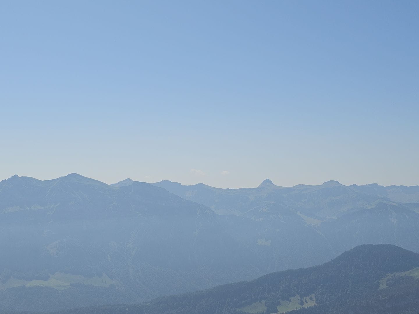 A blueish mountain ridge under light blue skies