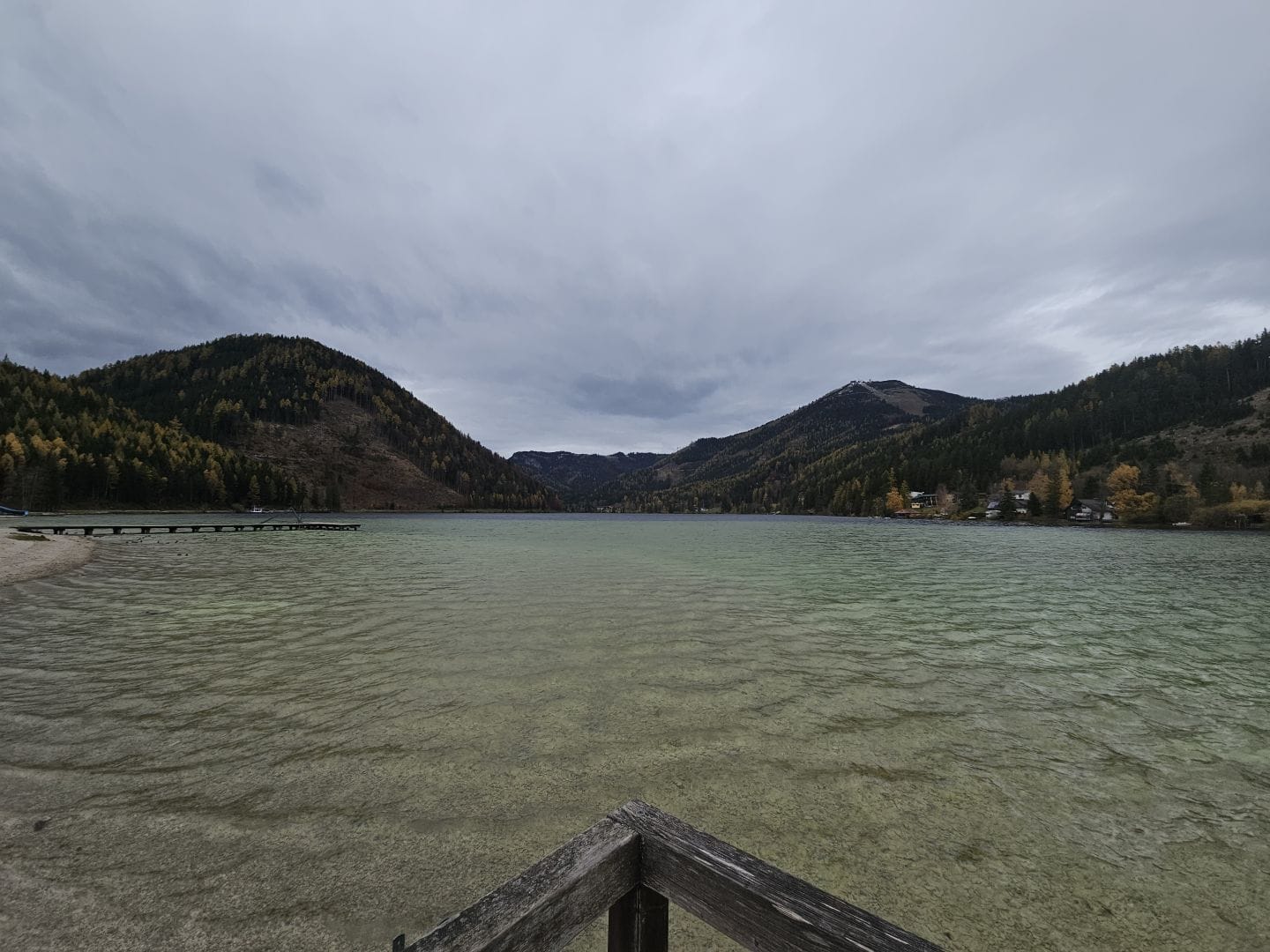 View of Erlaufsee in Styria. Greenish water against a background of hills and cloudy skies.