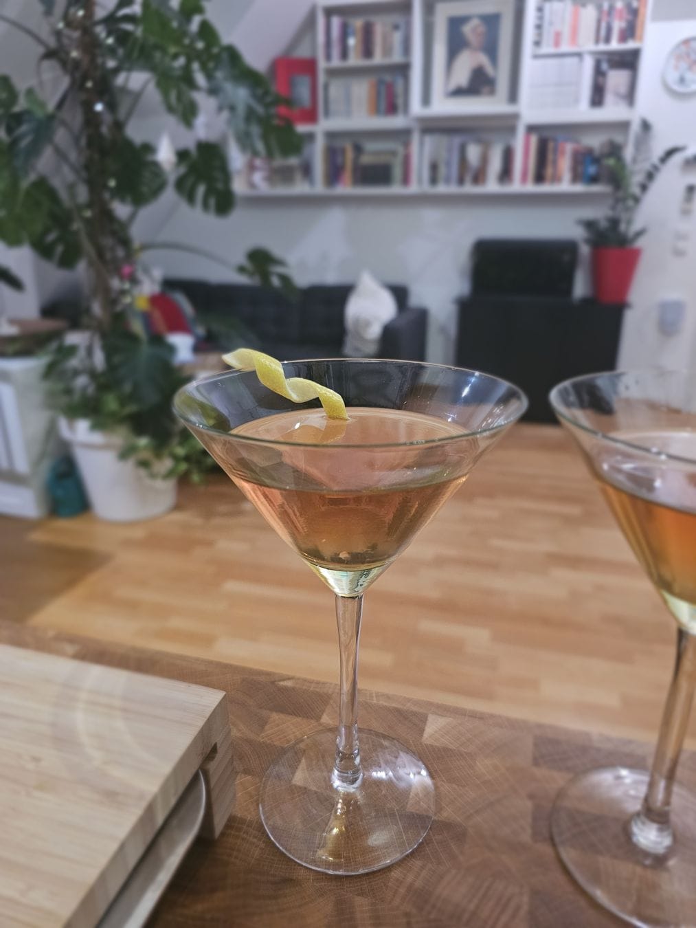 Cocktail glass filled with amber liquid and a lil lemon twist.