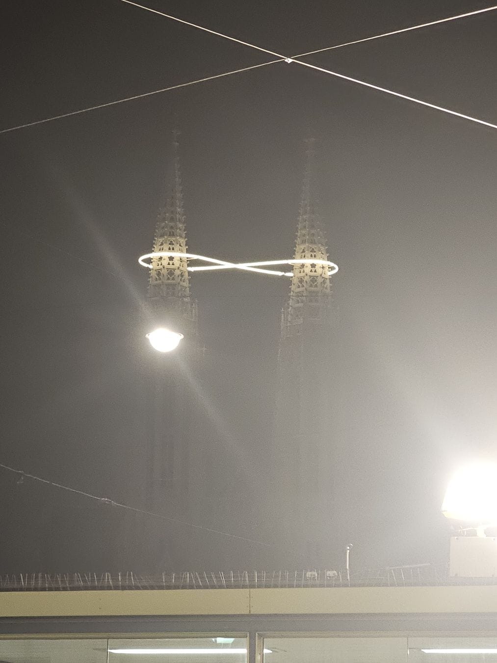 Votiv church at night, with an infinity loop, lit up, wrapped around its two towers.